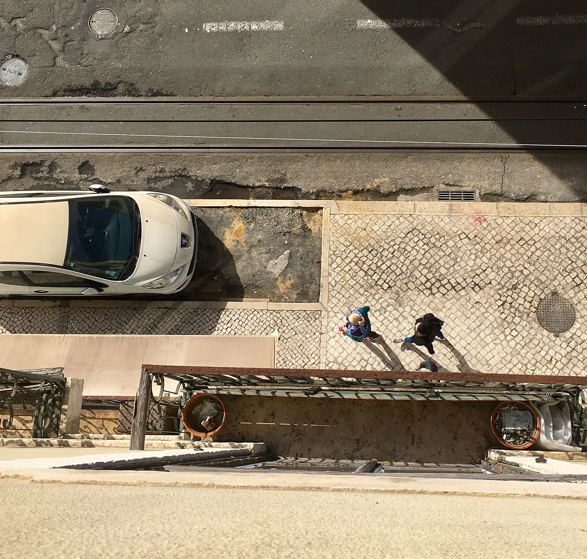 Aerial view of a Lisbon street with parked cars and pedestrians on traditional calçada portuguesa paving