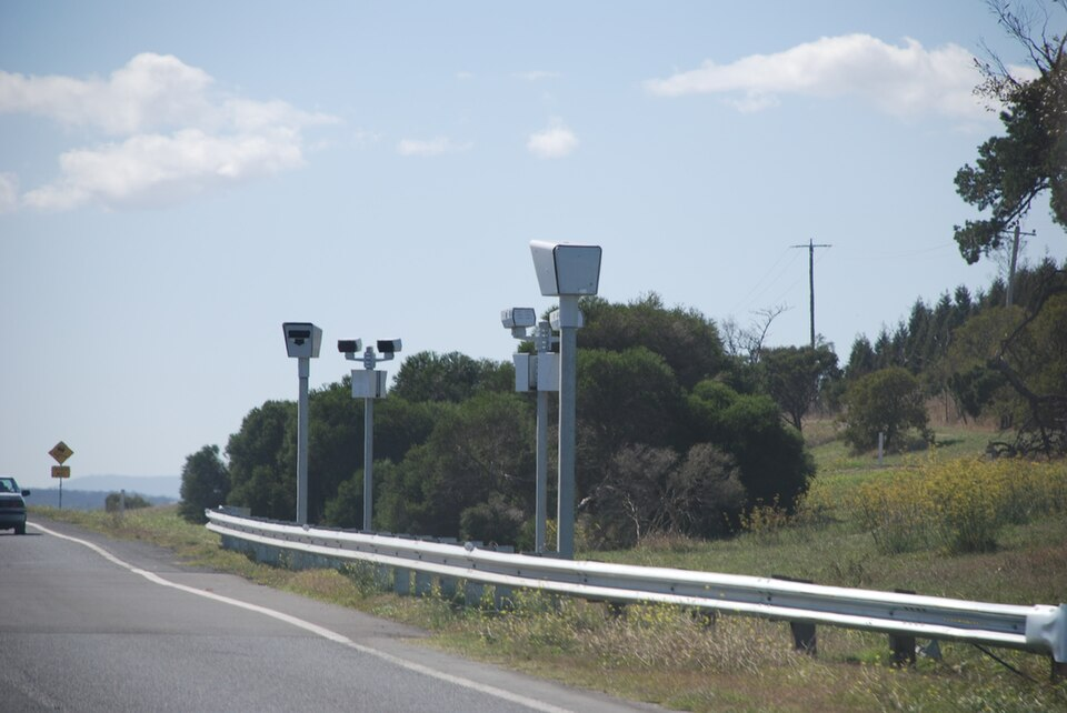 Automated speed cameras mounted on poles beside a highway