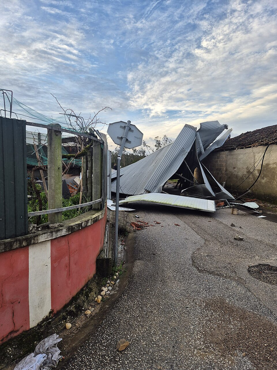 Storm damage from Storm Kristin, a collapsed metal roof and debris in the street